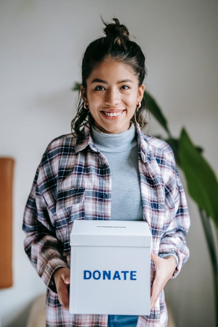 why-choose-us Cheerful woman holding a box labeled Donate indoors, symbolizing charity and kindness.